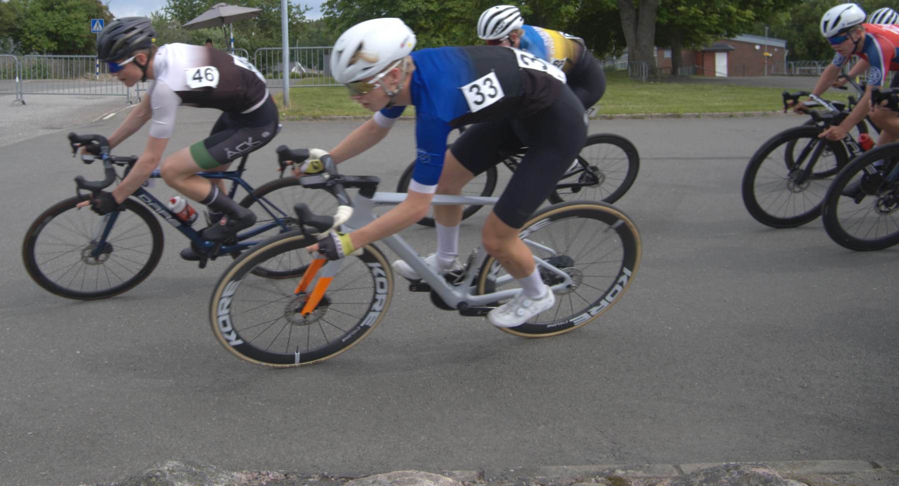 A pack of road cyclists leans through a corner side by side in a criterium.